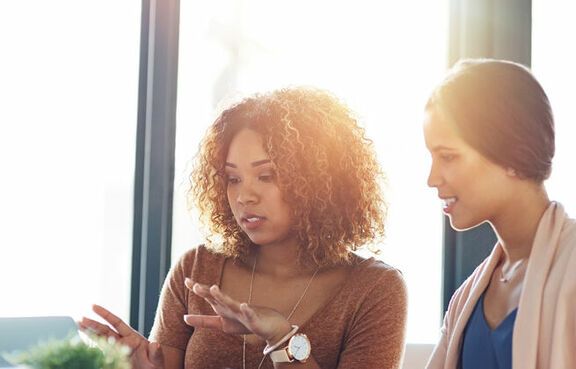 Two women at a desk looking at a laptop