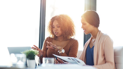 Two women at a desk looking at a laptop