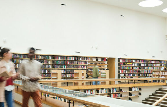 Students in motion walking through college library