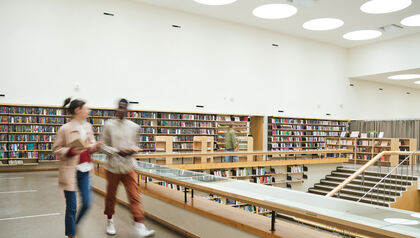 Students in motion walking through college library