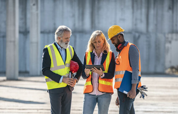 Group of professionals in safety vests meeting at a construction site