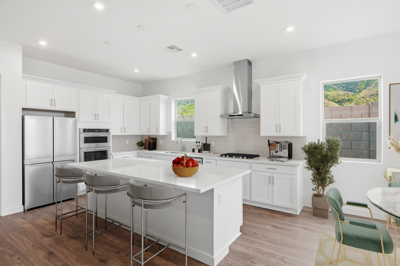 spacious kitchen with quartz countertops, grey barstools, and stainless-steel appliances