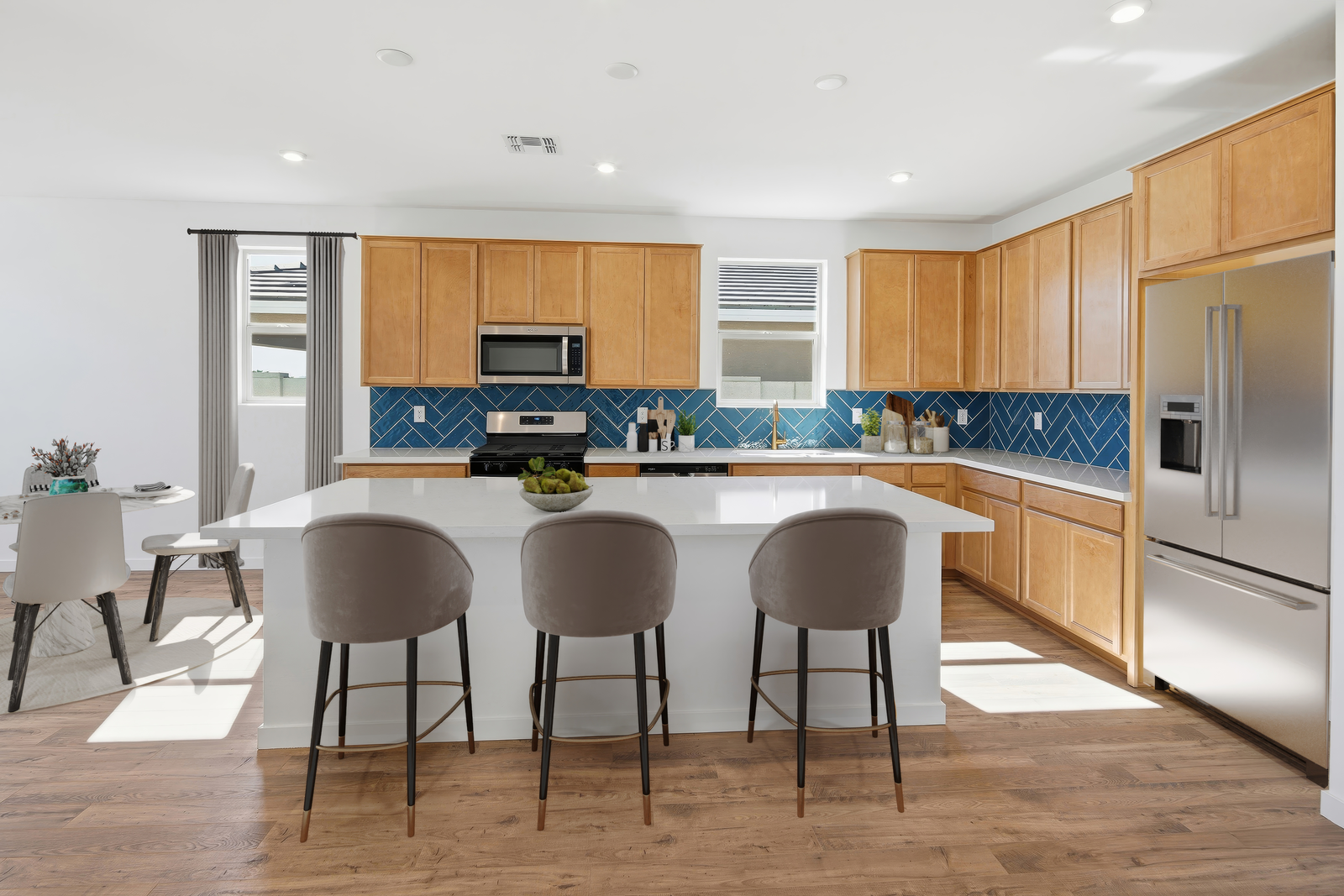 spacious kitchen with light brown cabinets, quartz countertops, and grey barstools