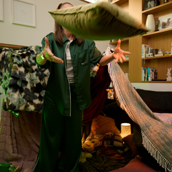 Cosy loungeroom fort build with olive green velvet cushion tossed in the air