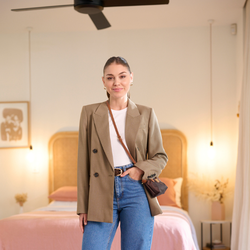 Lady wearing denim jeans, belt, white tank and brown blazer with a shoulder bag