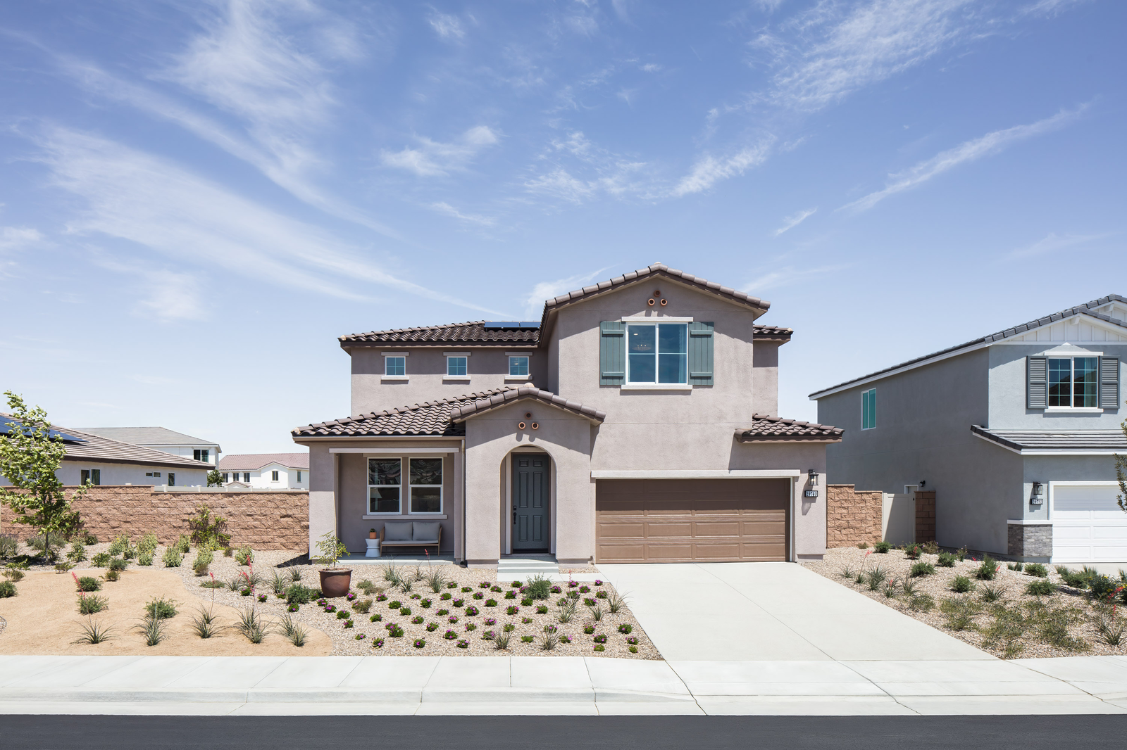 exterior of two-story home with brown garage and desert landscaping
