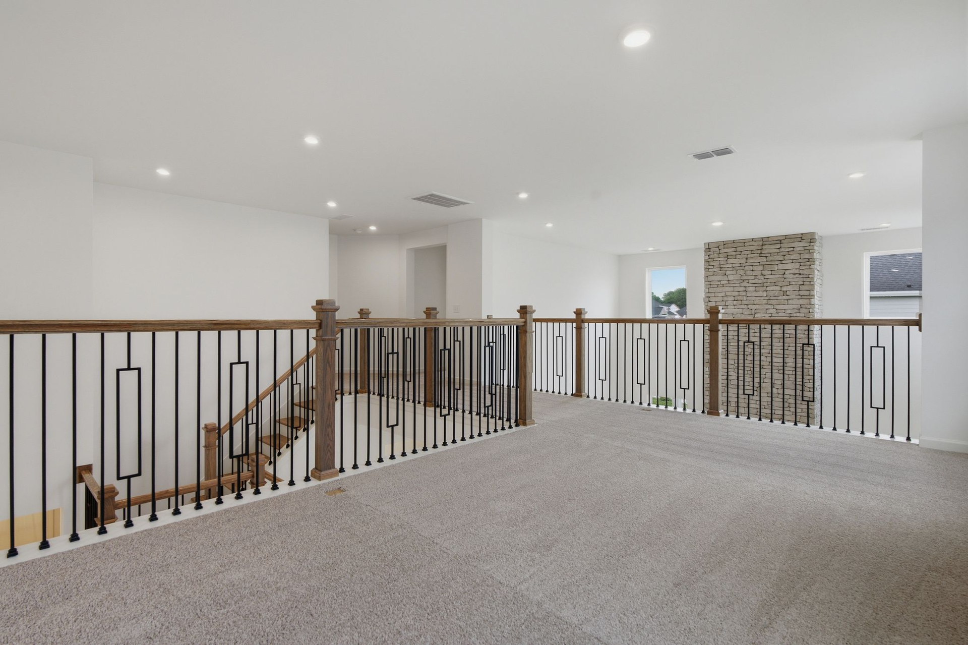 Loft with oak tread and iron railing, carpet, and large windows