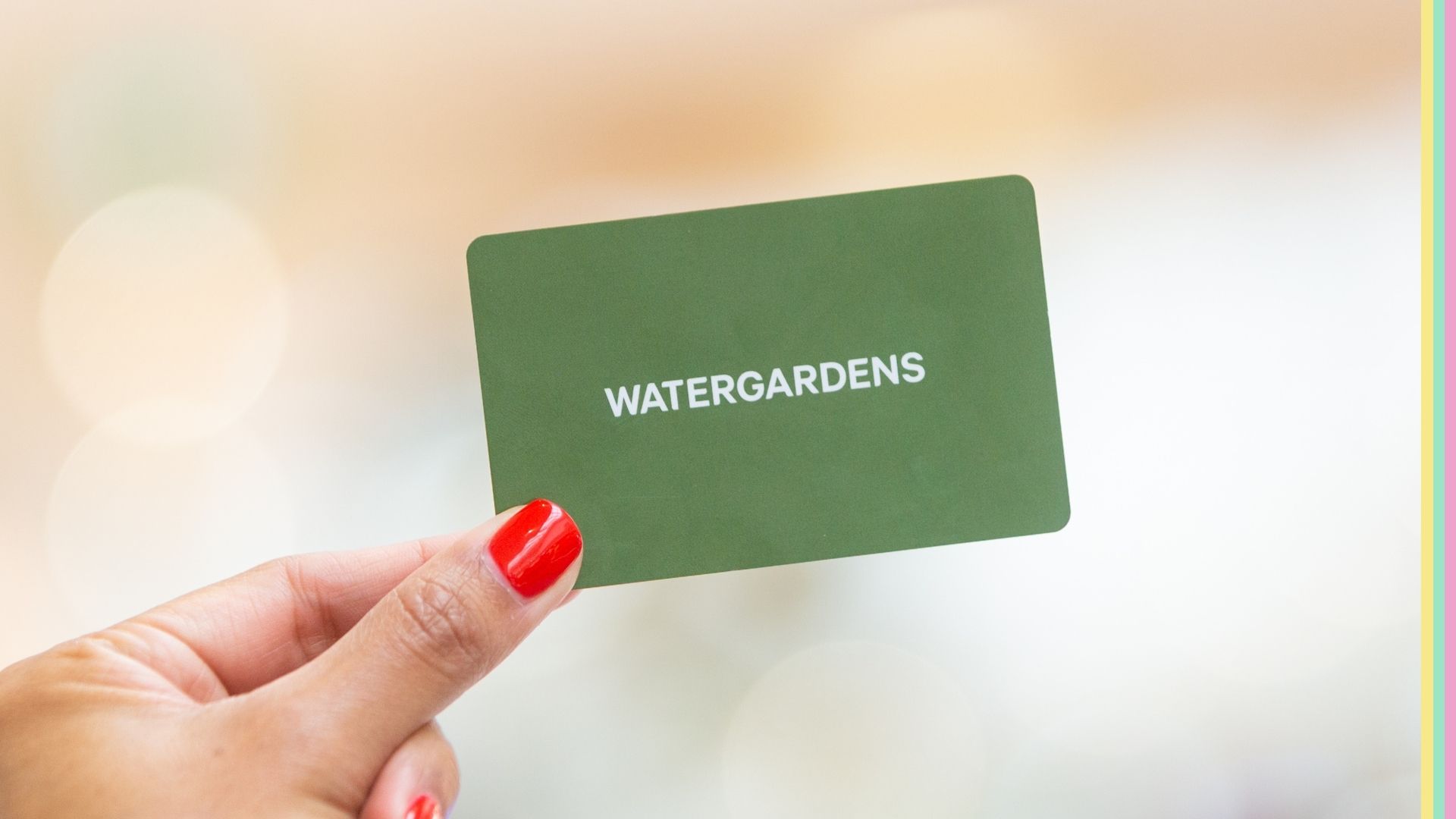 Woman's hand holding a Watergardens gift card.
