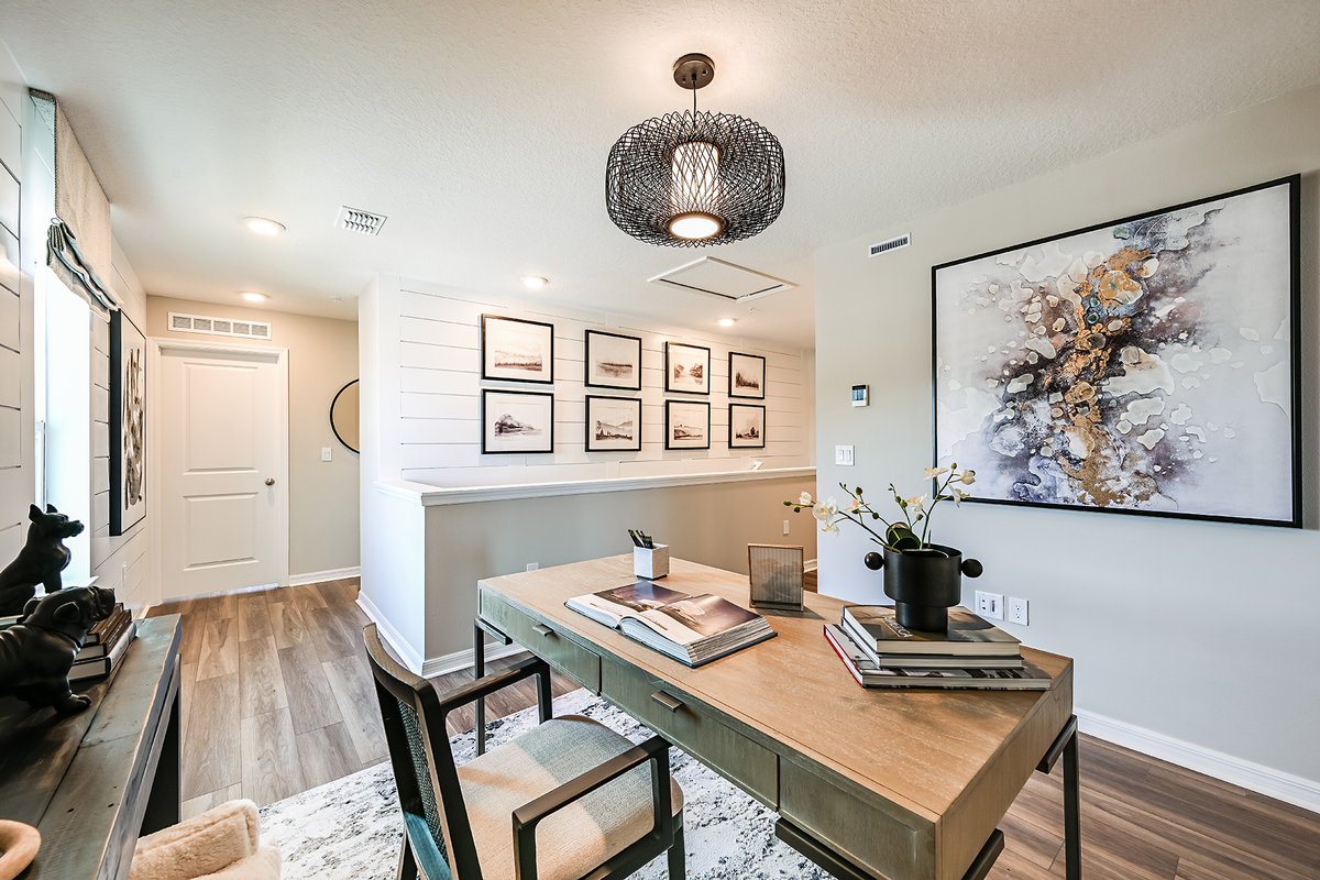 loft with desk, chair, and wall art