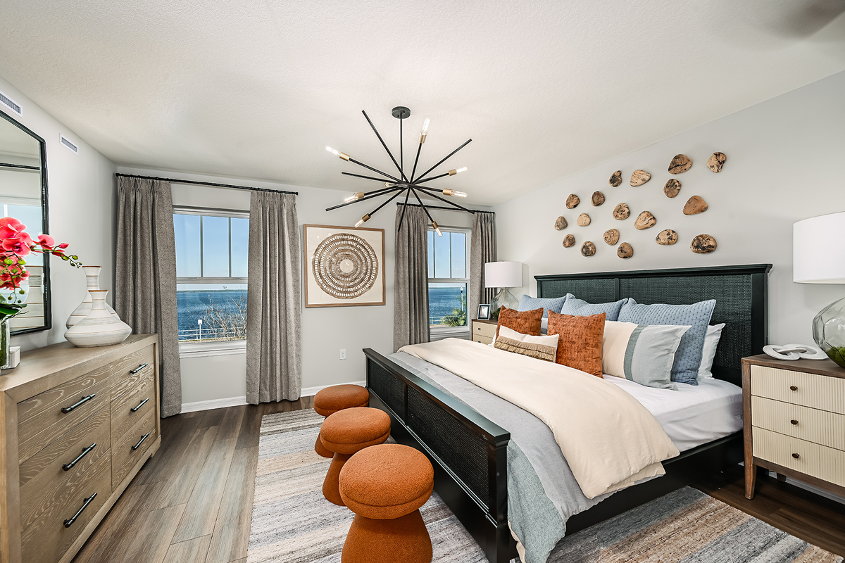 primary bedroom with black bed and orange stools
