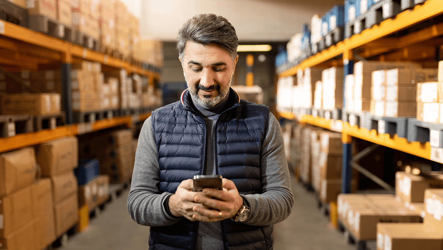 Image of a man standing in a warehouse looking at a handheld device.