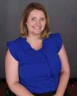 Erica Neal posing for headshot in blue blouse