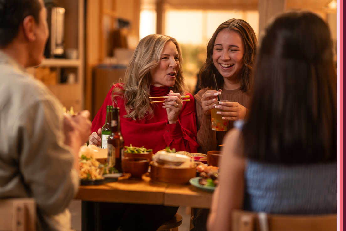 A mother and daughter laughing whilst dining in a restaurant. 