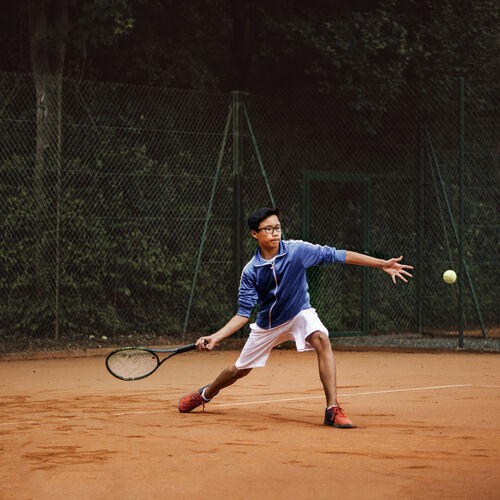 Un homme portant des verres de sport spéciaux HOYA pendant qu&#39;il joue au tennis