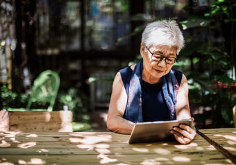 Una señora mayor con gafas de luz azul usando una tableta