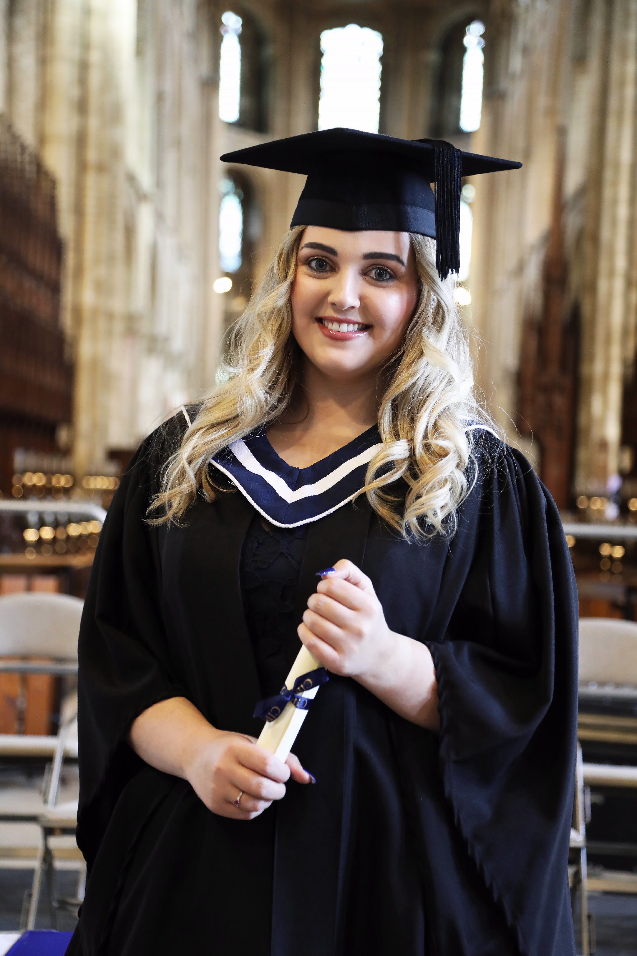 Female graduate holding a rolled diploma inside the cathedral