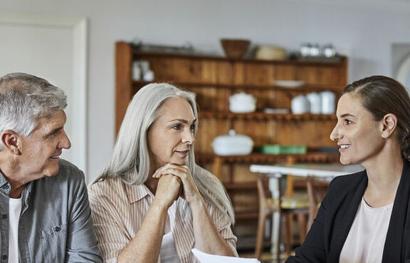 Financial advisor talking to a mature couple at a wood table