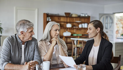 Financial advisor talking to a mature couple at a wood table