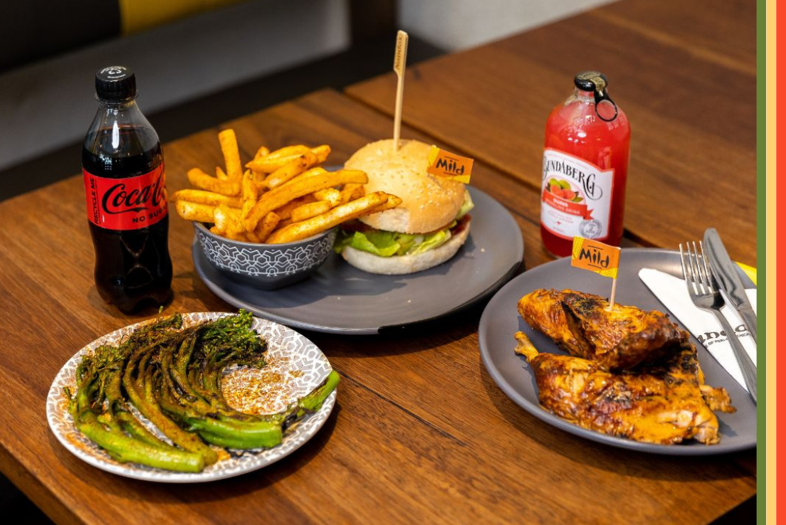 A variety of dishes including burger, chips, chicken and greens from Nandos. 