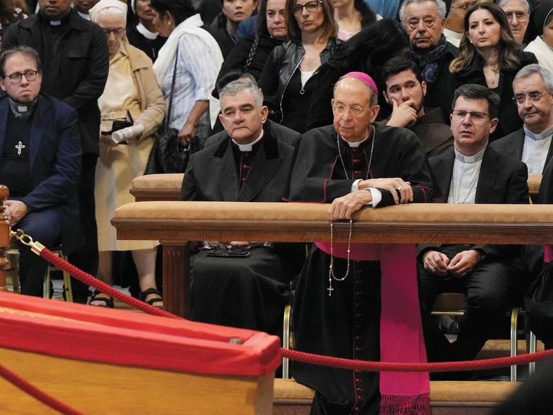 Archbishop William Lori kneels before the wooden coffin of Pope Francis