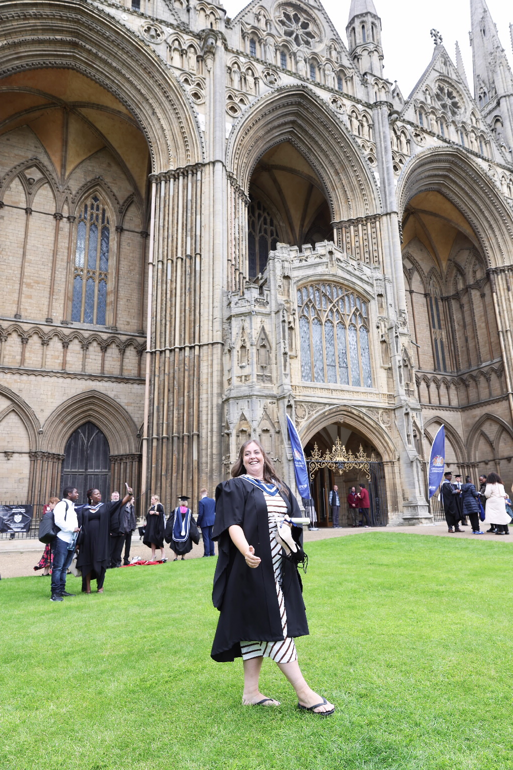 Graduate posing on a lawn in front of a grand cathedral entrance.