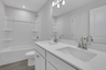 secondary bathroom with white cabinets and tile flooring