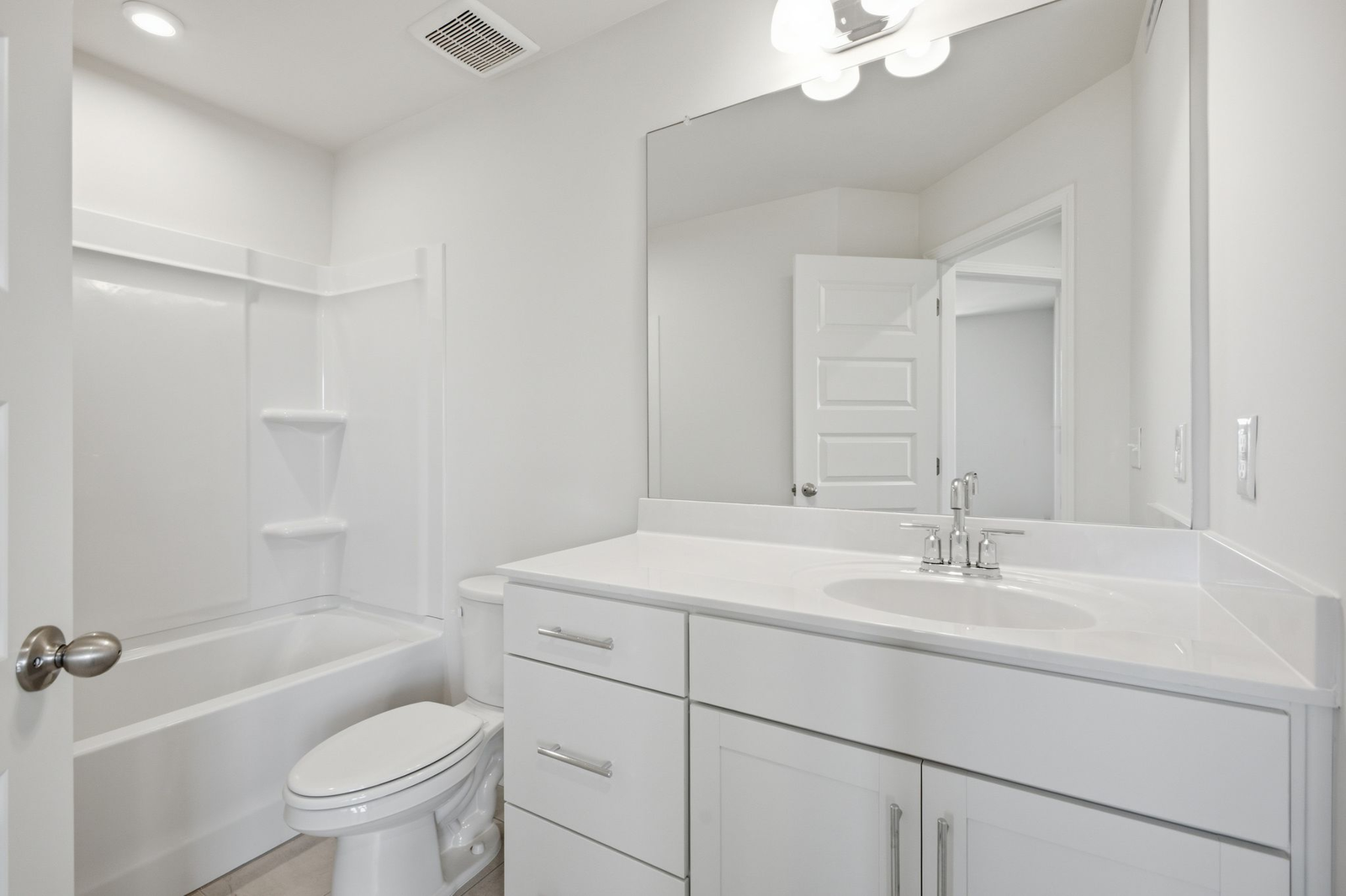 secondary bathroom with large tub, single-sink vanity with white counters and cabinets, polished chrome hardware