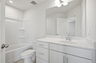 secondary bathroom with large tub, single-sink vanity with white counters and cabinets, polished chrome hardware