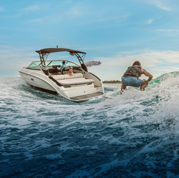 Man surfs the wake behind a white powerboat fitted with the Lenco SD Pro System