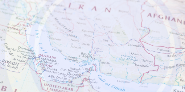 A close-up photograph of a physical world map showing the region around the Persian Gulf.The image is focused on the area including the eastern part of Saudi Arabia, the Persian Gulf, and the western part of Iran. Numerous country names are visible: SAUDI ARABIA, KUWAIT, IRAN, QATAR, UNITED ARAB EMIRATES, and OMAN. Major cities and features like RIYADH, DOHA, MANAMA (BAHRAIN), SHIRAZ, and THE GULF are clearly labeled.