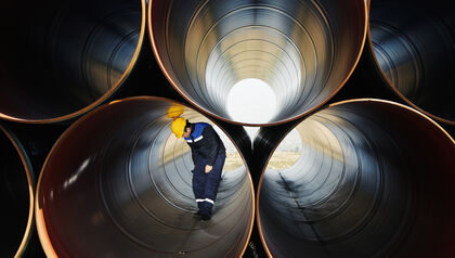 Large metal tubes stacked with a man inspecting one