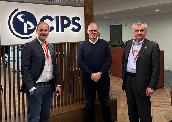 Three men in business casual attire standing together in front of a CIPS logo sign.