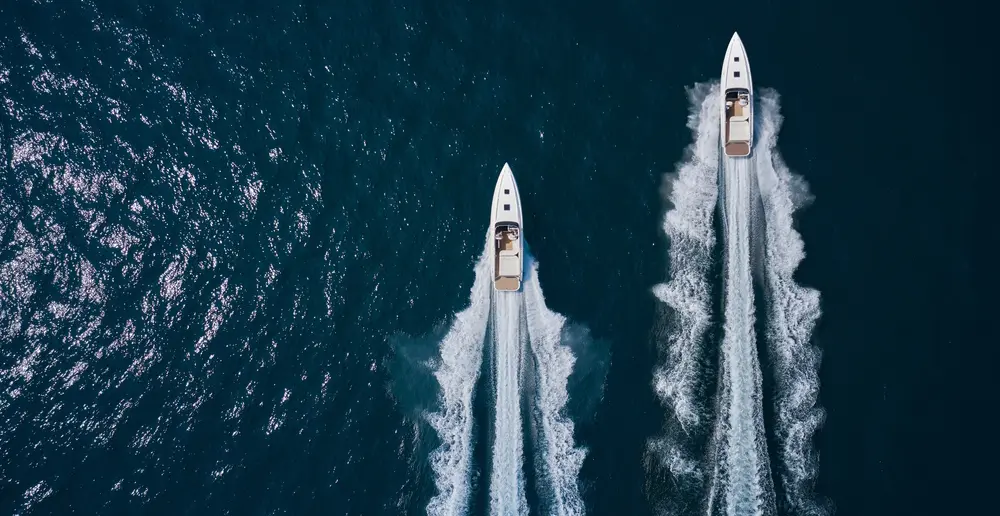 A birdseye view of water with two speedboats going in the same direction 