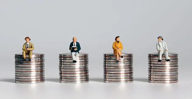 Four stacks of silver coins in a line with a single miniature plastic figurine sat on top of each stack 