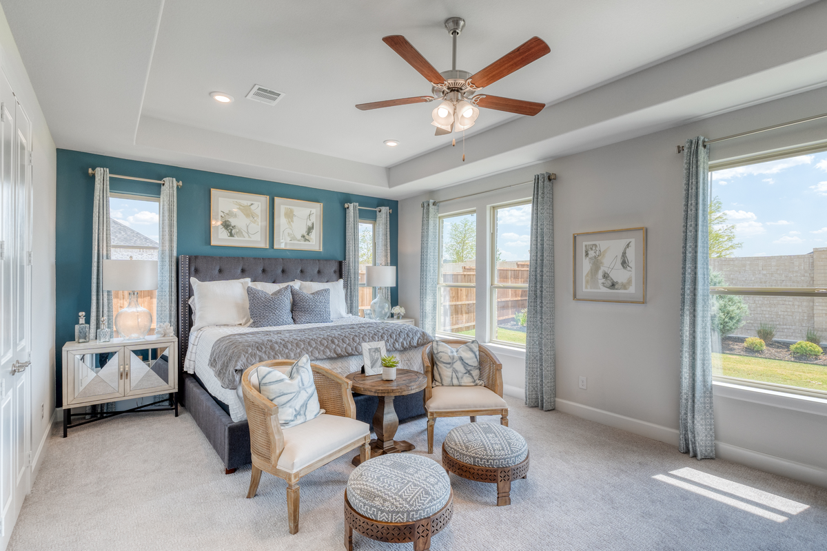 large primary bedroom with windows and carpet