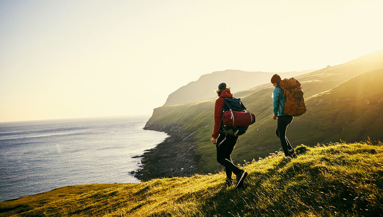 Two people hiking near the ocean on sunny day