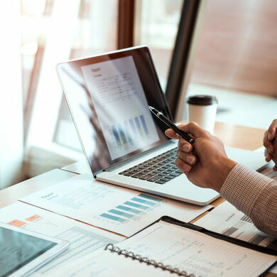 Manager sitting at a desk in front of a laptop looking at graphs