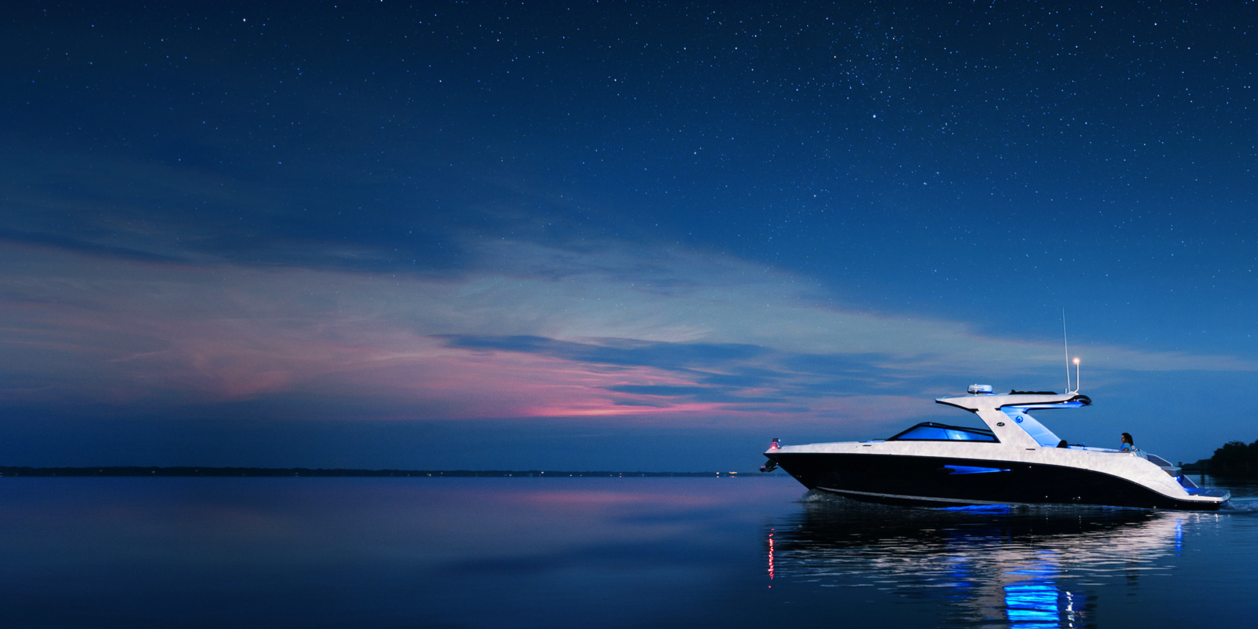 Powerboat with onboard Fathom e-power system at anchor on calm waters at blue hour