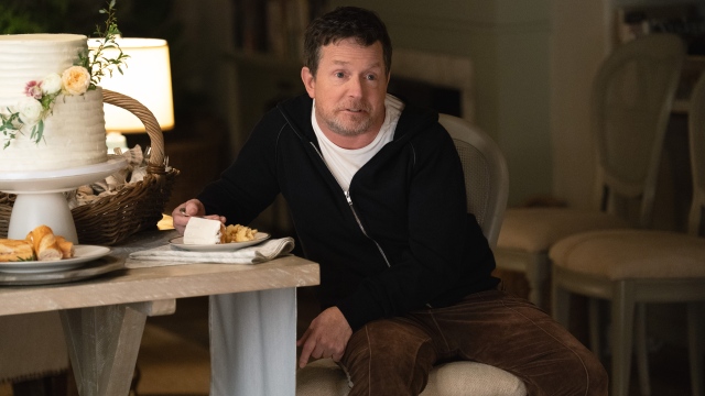 Michael J Fox as Gerry sitting in a chair eating food in Shrinking.jpg