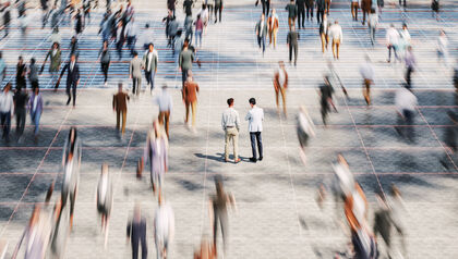 Two men standing still in a crowd of motion-blurred people
