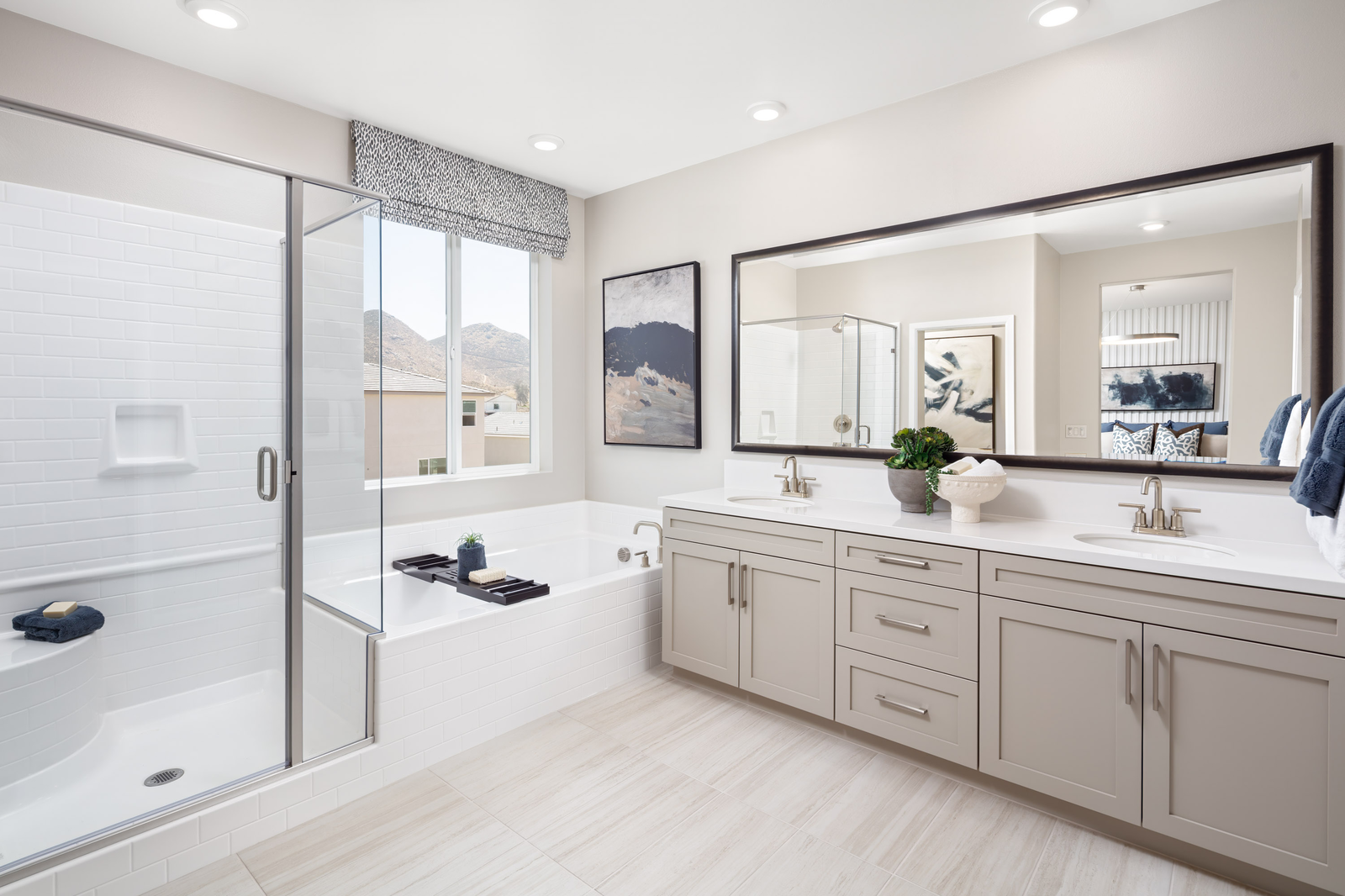 primary bathroom with white countertops and large window