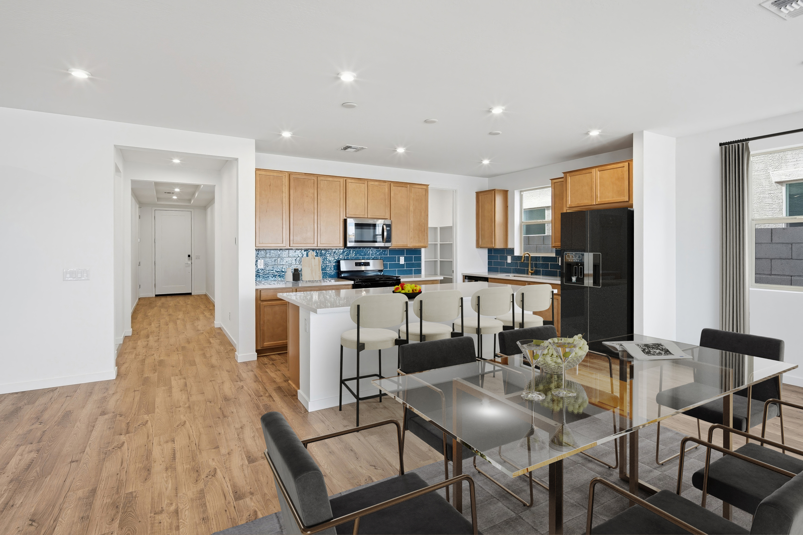 spacious kitchen with light brown cabinets, white barstools, and stainless-steel appliances
