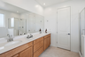 spacious bathroom with light brown cabinets, white countertops, and chrome faucets