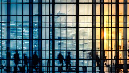 Silhouettes of people walking inside of glass office building