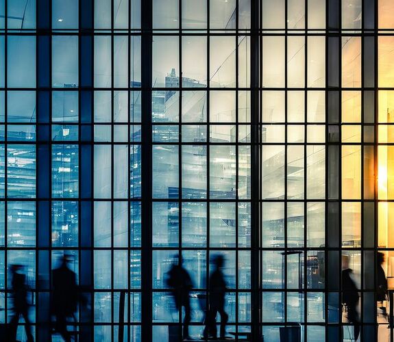 Silhouettes of people walking inside of office building
