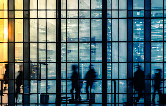 Silhouettes of people walking inside of office building