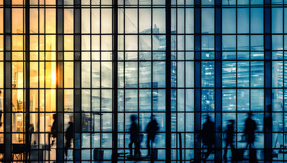 Silhouettes of people walking inside of office building