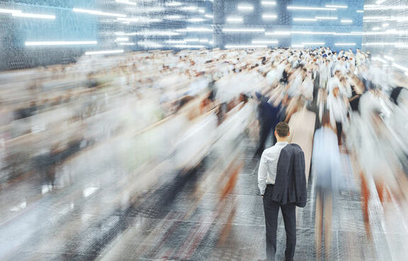 Man standing still in a crowd of blurred, fast-moving people