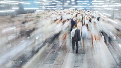 Man standing still in a crowd of blurred, fast-moving people