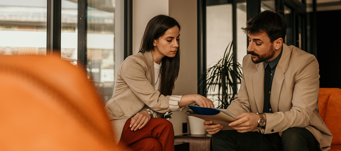 A woman showing a man something on paperwork.